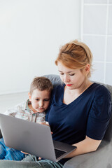 Beautiful woman with son online on computer at home