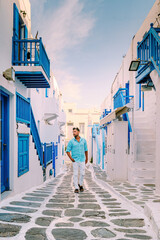 Mykonos Greece, Young man at the Streets of old town Mikonos during a vacation in Greece, young men on vacation holiday in Europe walking at Little Venice Mykonos Greece. - obrazy, fototapety, plakaty