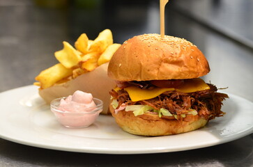 Delicious burger with beef, tomato, cheese and lettuce.serving  cheeseburger with dressing and pomes frites, 