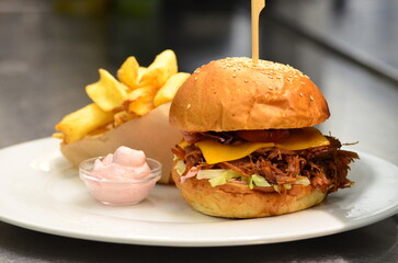 Delicious burger with beef, tomato, cheese and lettuce.serving  cheeseburger with dressing and pomes frites, 