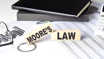 MOORE'S LAW - text on a wooden block with chart and notebook