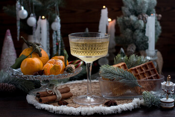 New Year's table setting with dessert waffles and tangerines.Festive atmosphere with candles and a green Christmas tree, romance