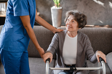 Cropped photo of happy pensioner grandmother elderly patient with walking frame with assistance of...