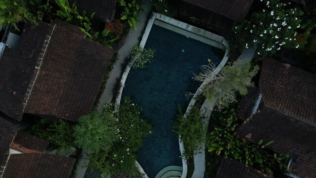 Aerial view of Traditional Tourist Resort with pool and tropical garden in Bali, Indonesia. Concept for tropics tourism, holiday and exotic asia tropical island beach. Swimming pool with trees around.