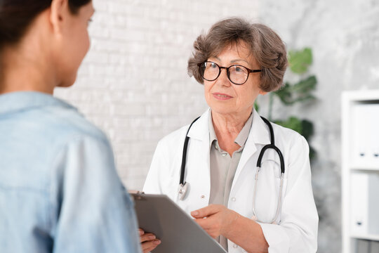 Female senior doctor explaining telling diagnosis to woman patient, showing test results, diagnosis, prescribing medications pills drugs at hospital