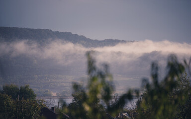 Low rain clouds in misty forest. The lifting of the fog at dawn. The water cycle in nature