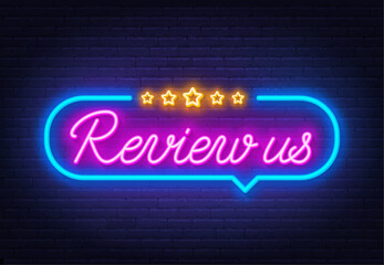 Review Us neon sign in the speech bubble on brick wall background.