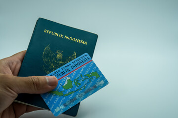 man's hand holding Indonesian ID card and passport