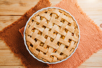 Apple pie in blue form on a light wooden background with a brown kitchen towel. Ready pie. Top view