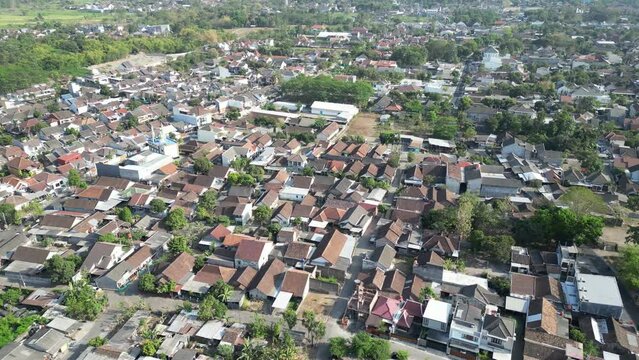 Aerial view of Jogja City with buildings, crowded vehicles traffic in morning sunlight. Sleman cityscape urban landscape. Population density is displacing agricultural land and forests.