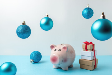 Piggy bank with Christmas decoration on blue table. Christmas or New Year minimal concept.
