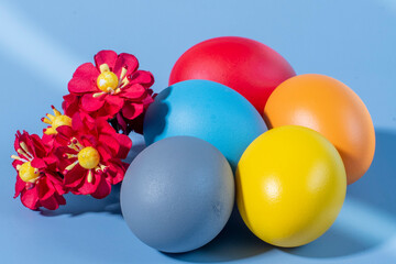 Colorful eggs, symbolizing Easter, on a colorful background and flowers