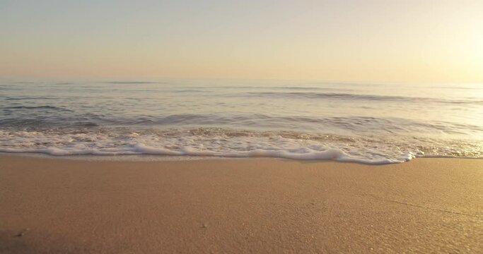 Calm ocean water waves splashing sandy beach. Closeup small blue sea waves breaking sand beach