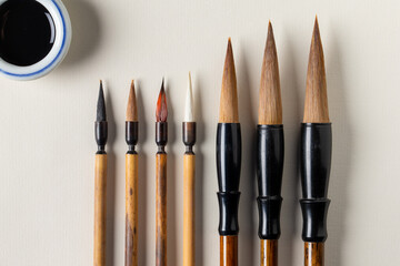Pinceaux en bois pour la calligraphie, de taille différentes et alignés avec pot à encre