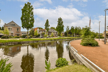 Canal amidst houses and trees under sky