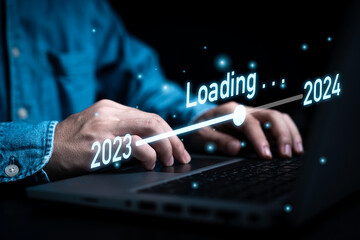 Businessman using laptop computer with downloading tool bar for countdown 2023 to 2024 , Merry Christmas and happy new year preparation by technology concept.