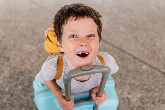 Cheerful kid with baggage from above