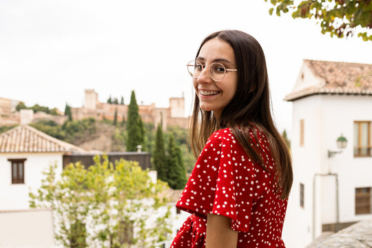 Smiling tourist standing while looking at camera against Alcazaba in town