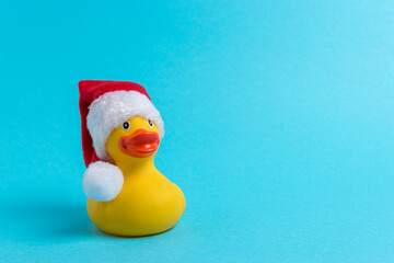 Rubber duck with Santa hat on blue background. Minimal Christmas or New Year concept.