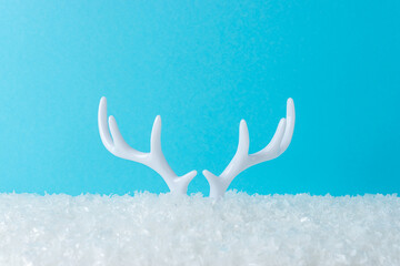 White reindeer antlers on snow with bright blue background. Minimal New Year or Christmas concept.