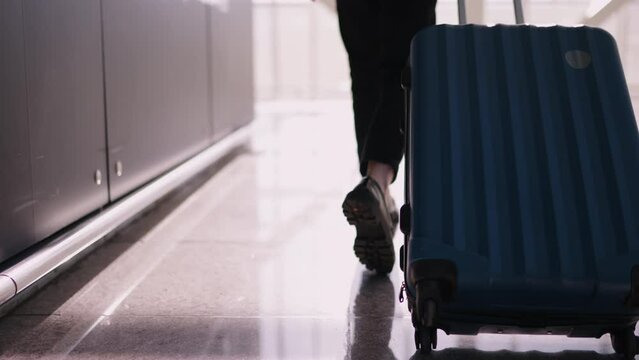 Close-up of suitcase being pulled by young woman passenger, details indicating moment during business trip at airport,focus on concept of travel and mobility. Female traveler walk to gate with luggage