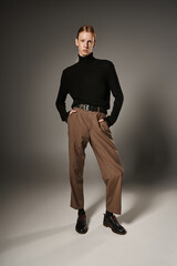 vertical shot of attractive androgynous model in trendy attire posing with hands in pockets, fashion