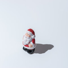 Small Santa Claus with strong shadows on white background. Creative Christmas or New Year concept.