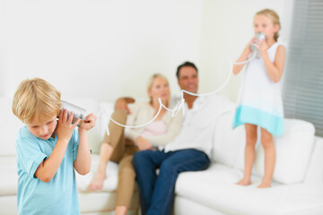 Home, family and children with tin can, playing and fun in a living room, love and bonding together. Parents on a sofa, mother and father with kids, apartment or communication with smile, game or joy