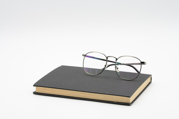 Reading glasses on black book isolated on white background
