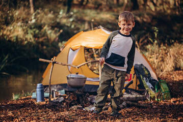 The boy near a tent and fire. Camping.