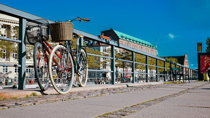 Czerwony i czarny rower oparte o barierkę w starej części   miasta Kopenhaga w Danii. - obrazy, fototapety, plakaty