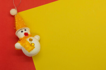 Snowman and Christmas decoration on yellow and red background with copy space