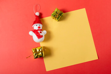Christmas greeting card with Snowman and gift boxes on red background.