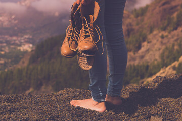Concept back view of female people barefoot with broken shoes on hand admiring landscape panorama. Travel and poverty human. Freedom and nature background outdoors valley view. Copy space wanderlust - obrazy, fototapety, plakaty