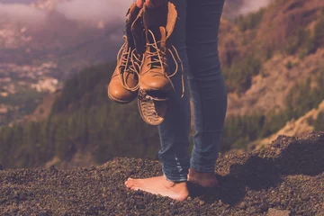 Foto op Canvas Concept back view of female people barefoot with broken shoes on hand admiring landscape panorama. Travel and poverty human. Freedom and nature background outdoors valley view. Copy space wanderlust © simona