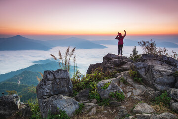 Obraz premium Young woman in red jacket hiking on the high mountain, Doi Pha Tang, Chiang Rai province, border of Thailand and Laos.