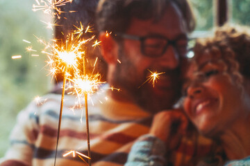 Love and romantic leisure activity with man and woman holding fire sparkler light together hugging...