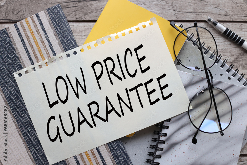 Poster low price guarantee text on paper. different notepads on the table