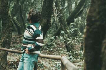 One man standing in the outdoors park footpath enjoying and admiring high beautiful green trees...