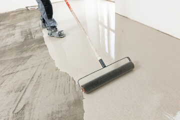Master with needle roller for new screed concrete with mixture of cement for leveling for floors....