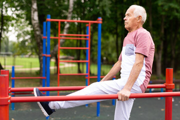 Senior man exercising at parallel bars outdoors