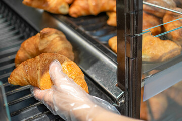 Hand taking Croissants stored for sale and consumption. Popular French pastries