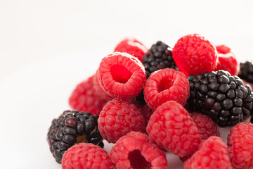 Handful of raspberry and blackberry berries on white background
