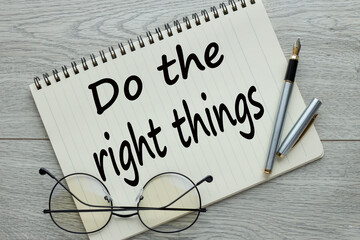 Do the right thing. Workplace with a notepad and glasses with a pen on a wooden table. text on the...