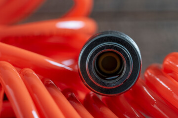 An orange air hose with an hose coupling on a black background, closeup. Detail of air compressor hose and pistol - obrazy, fototapety, plakaty