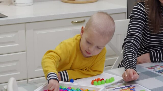 mother and child playing together pegboard mosaic. Early child development. Fine motor skills. Learning and creativity