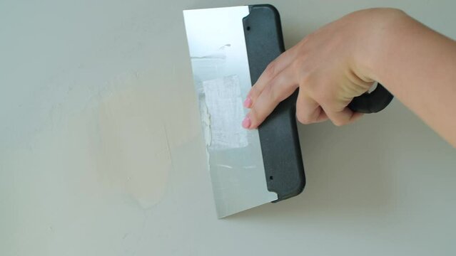 Woman hand plastering wall with spatula. Plasterer applying putty of joints on finishing works. DIY house renovation, interior design concept. Slow motion