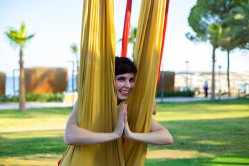 A woman took a yoga pose while doing aerial gymnastics on fabrics.