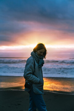 Young woman walking near ocean at sunset. beauty of loneliness and sadness