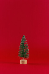 Green Christmas tree on red background. Minimal Christmas or New Year holiday concept.
